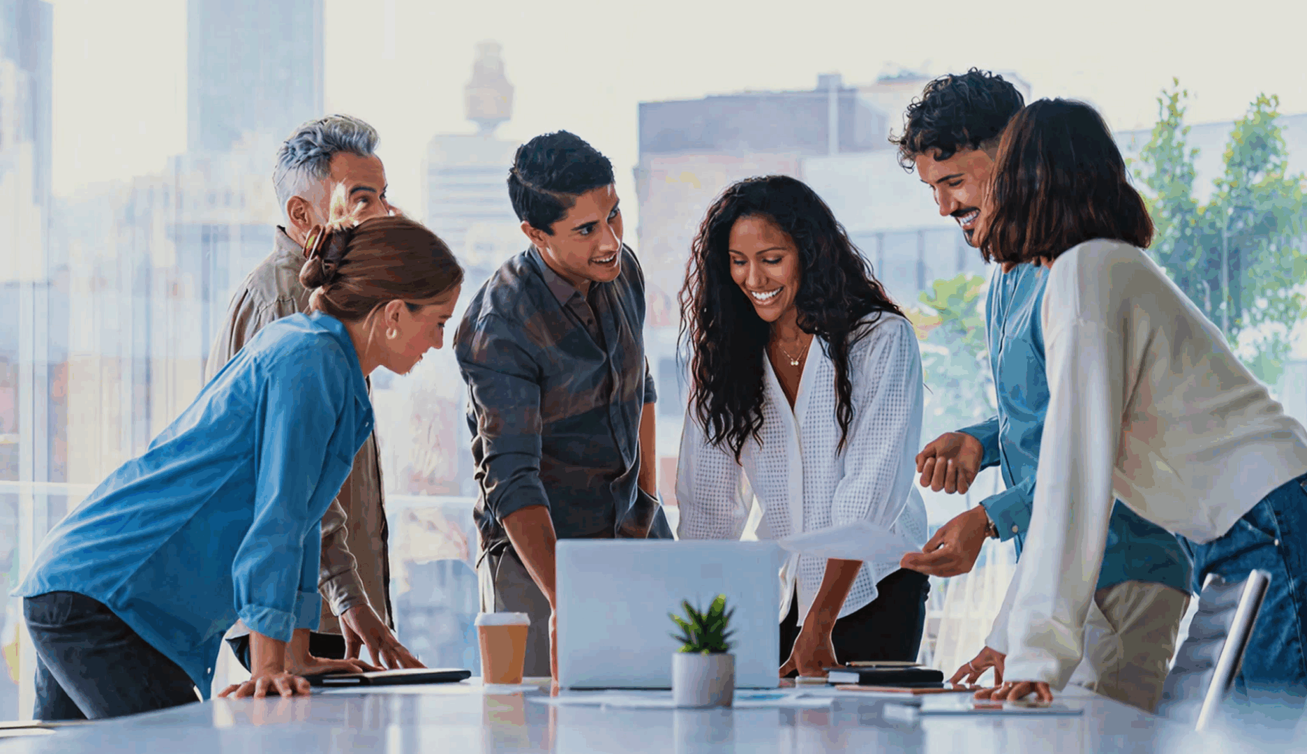 Group collaborating around a laptop in office.